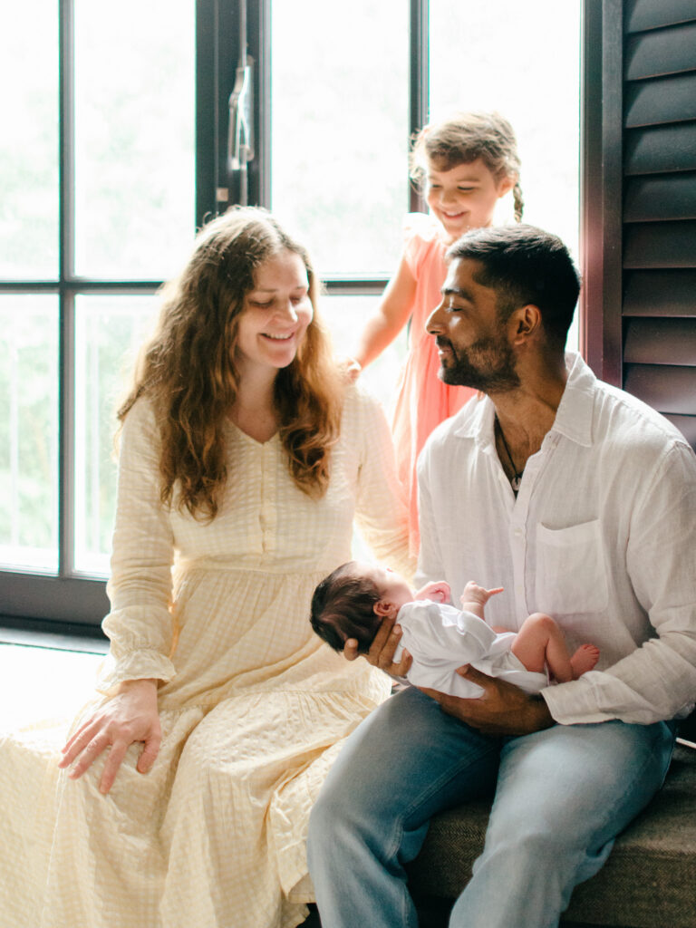 A family of four laugh on a windowsill in their living room in Oud West.