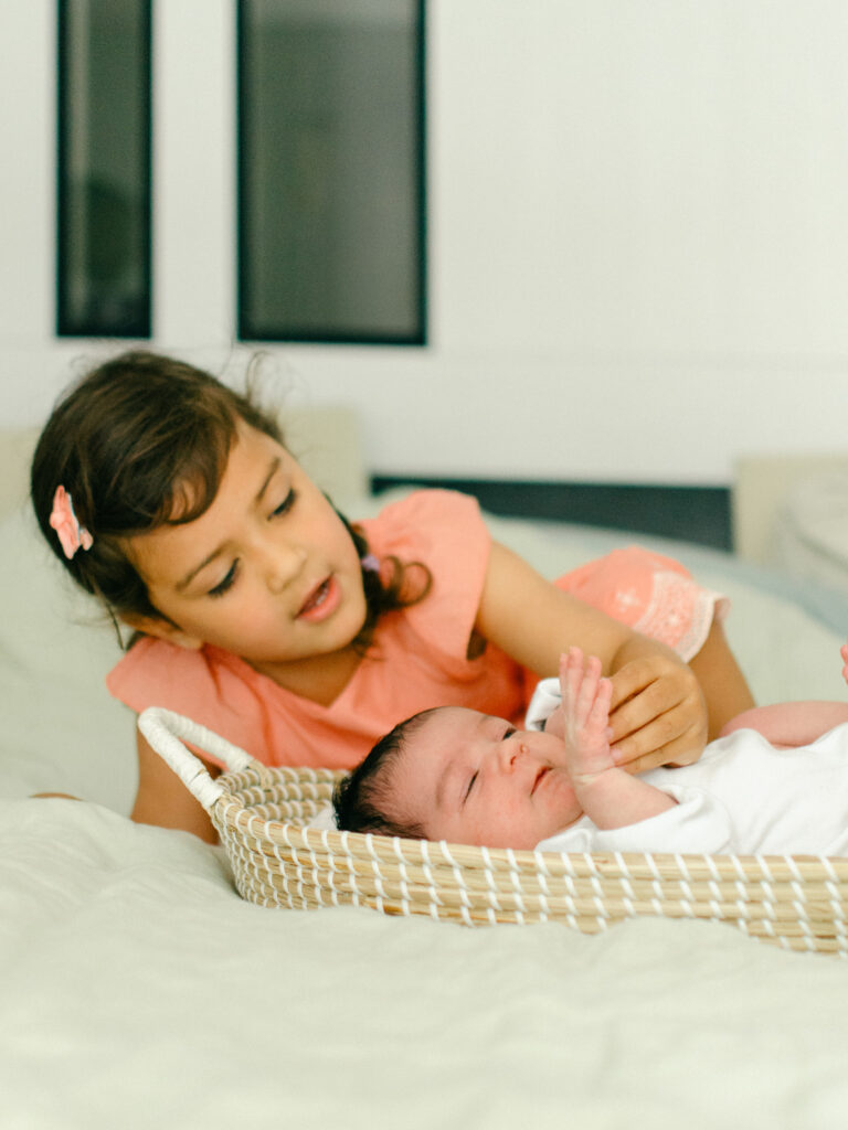 Big sister counts her newborn sister's fingers.