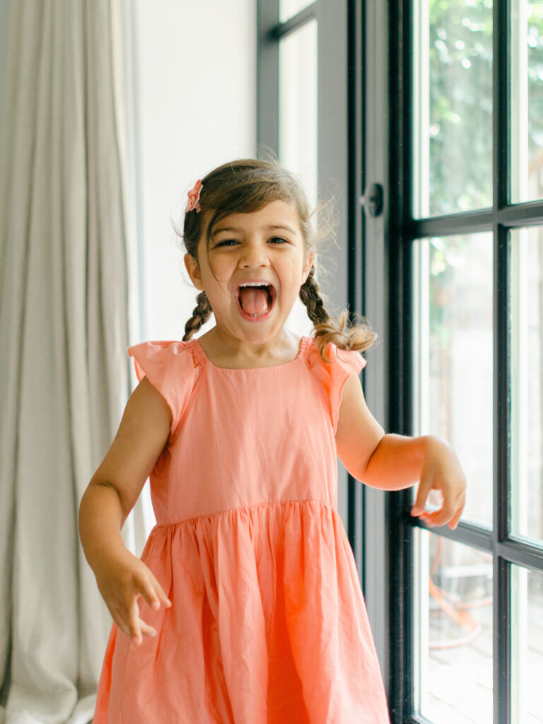 Big sister dances excitedly during her baby sister's newborn photoshoot.