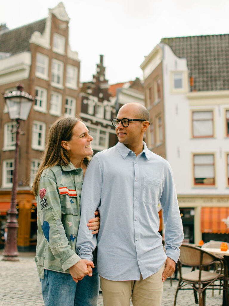 Romantic photos of a couple in Amsterdam, with the historic houses behind them. 