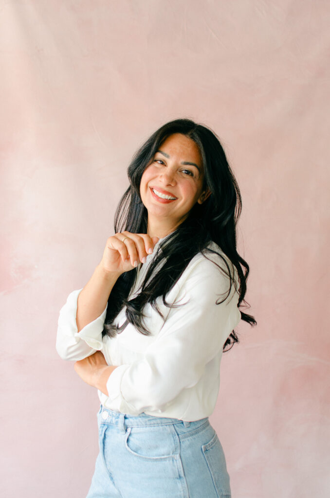 Woman in white shirt smiles for professional headshots in Amsterdam against a hand-painted backdrop.