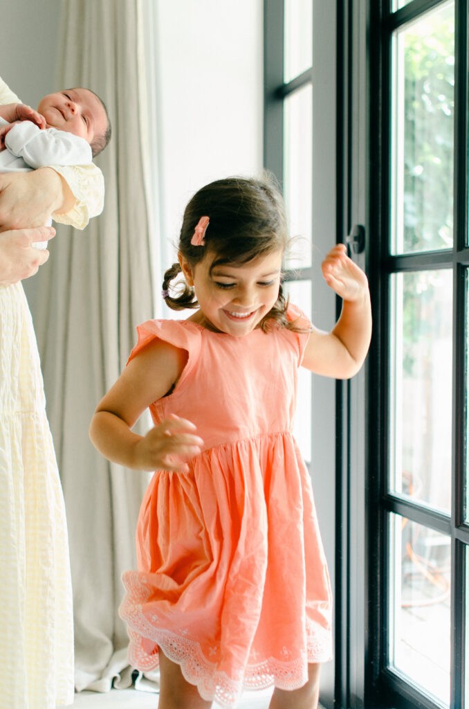 Big sister dances during her baby sister's newborn shoot.