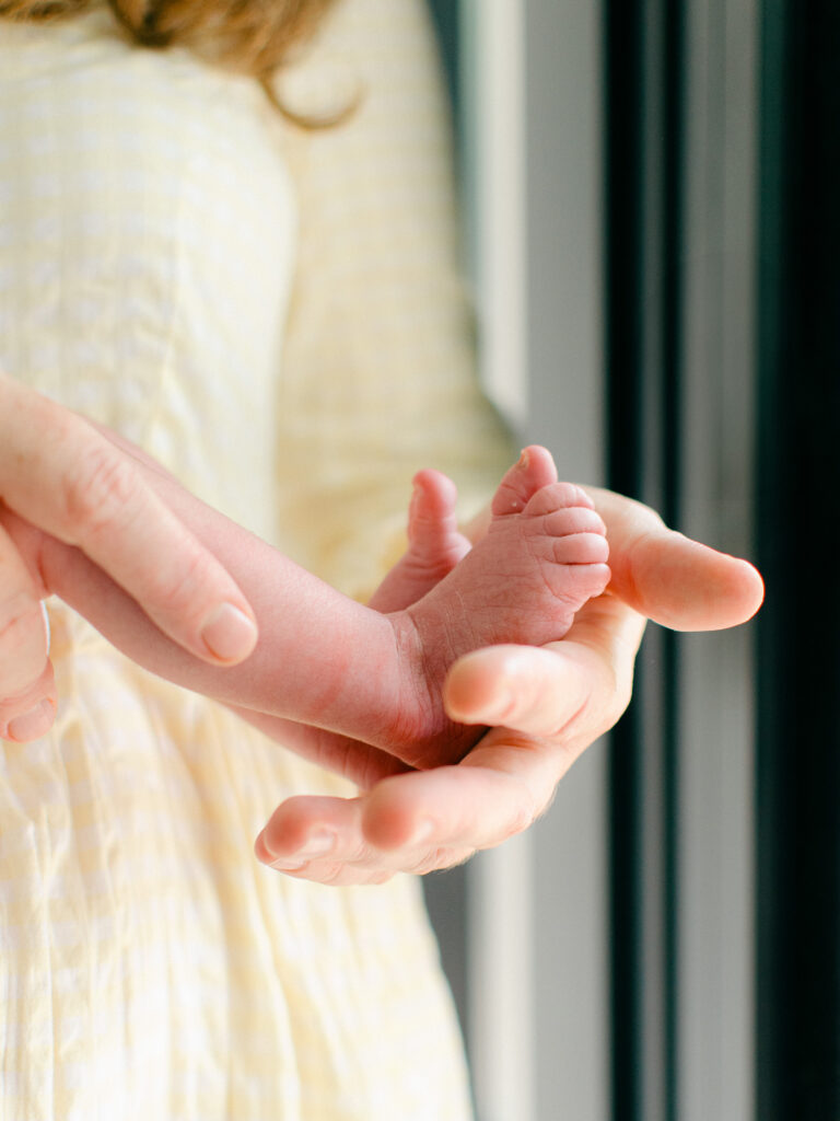 Mom cradles her newborn baby's little tiny feet during a home photoshoot in Oud-West.