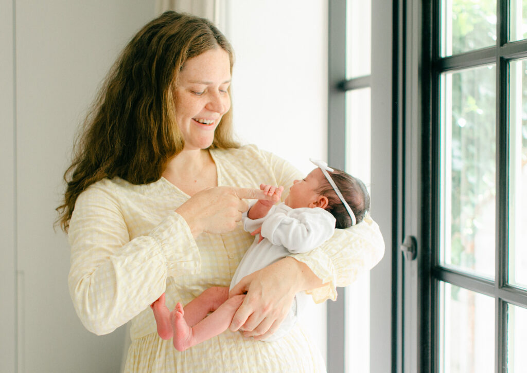 Baby grabs her mom's fingers with her whole hand.