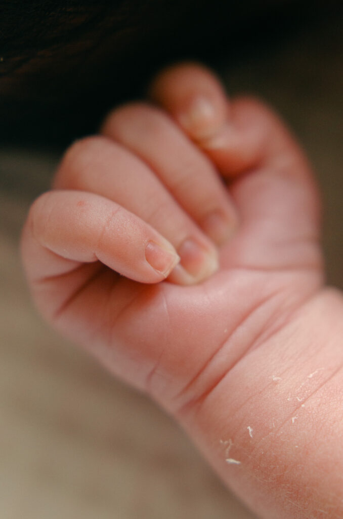 Macro image of a newborn baby's little fingers during an in-home photoshoot.