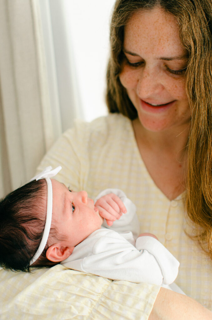 Mom dressed in yellow cradles her baby girl.
