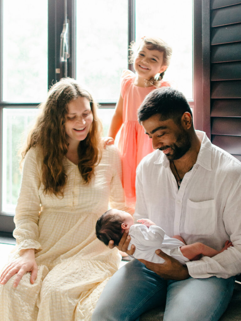 Family smiles at their newest addition during a newborn photoshoot.