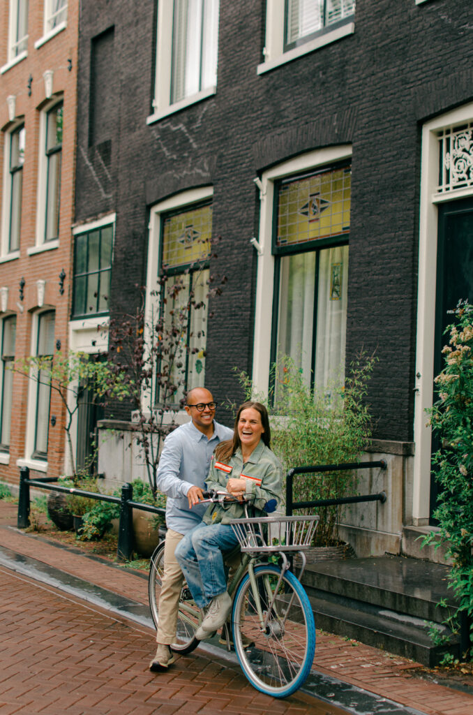 Woman sits on a bike while her partner pushes up up a canal in Jordaan, Amsterdam.