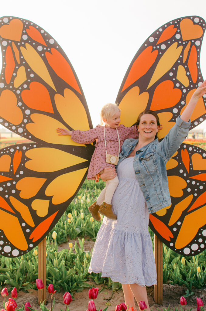 mother and daughter pose with a giant butterfly in the tulip barn